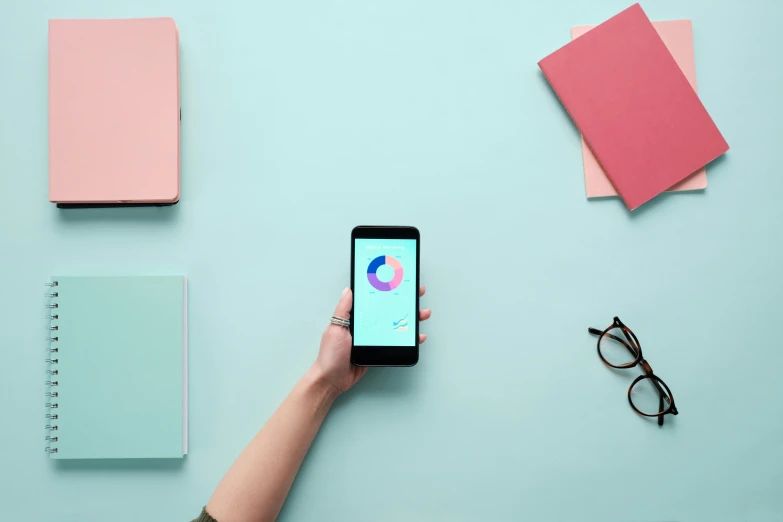 a person holding a smart phone on top of a table, trending on pexels, pink and teal, 9 9 designs, schools, modern minimalist f 2 0