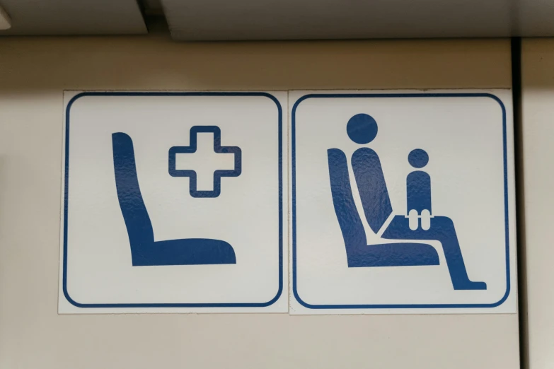 a close up of a blue and white sign on a wall, sitting in a chair, the other is used for flight, pictogram, nursing