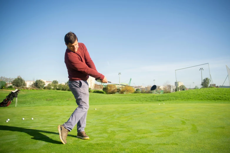 a man swinging a golf club at a golf course, a picture, pexels contest winner, happening, amr elshamy, casually dressed, maroon, a green