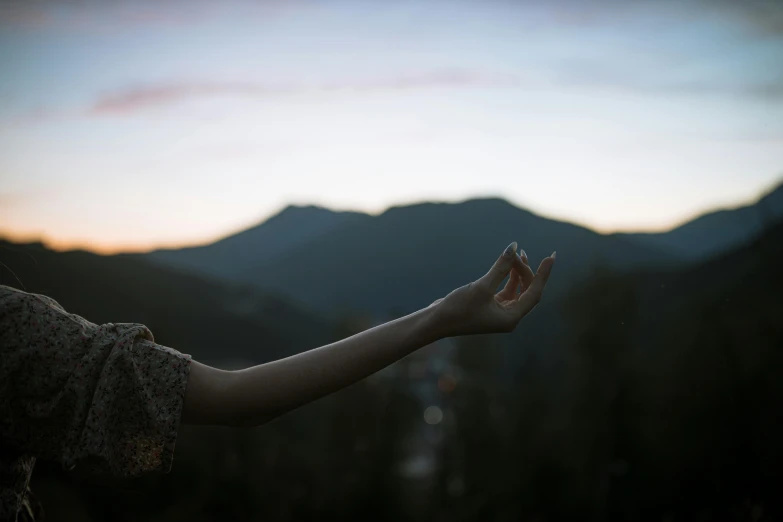 a person holding their hands out with mountains in the background, inspired by Elsa Bleda, pexels contest winner, summer evening, anjali mudra, medium format. soft light, portrait shot