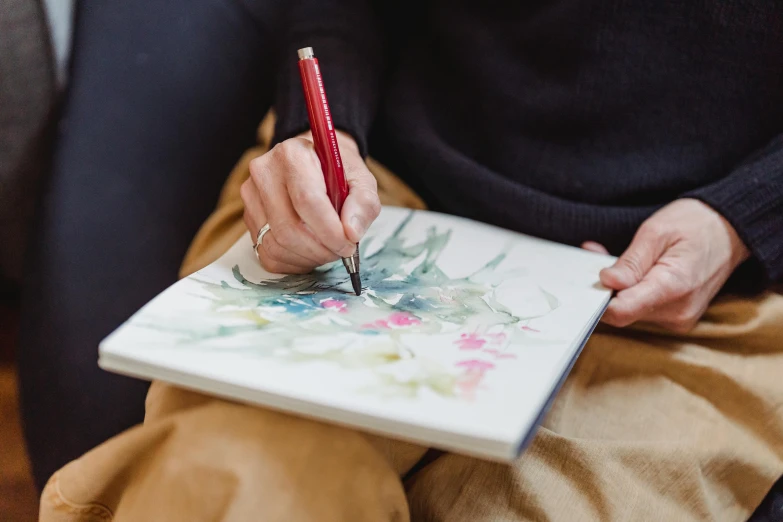 a close up of a person holding a pen and a notebook, inspired by artist, watercolours, mate painting, botanical drawing, professional artwork