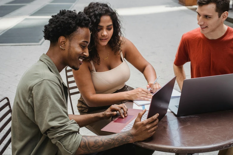 three people sitting at a table with a laptop, pexels contest winner, happening, varying ethnicities, college, holding notebook, urban setting