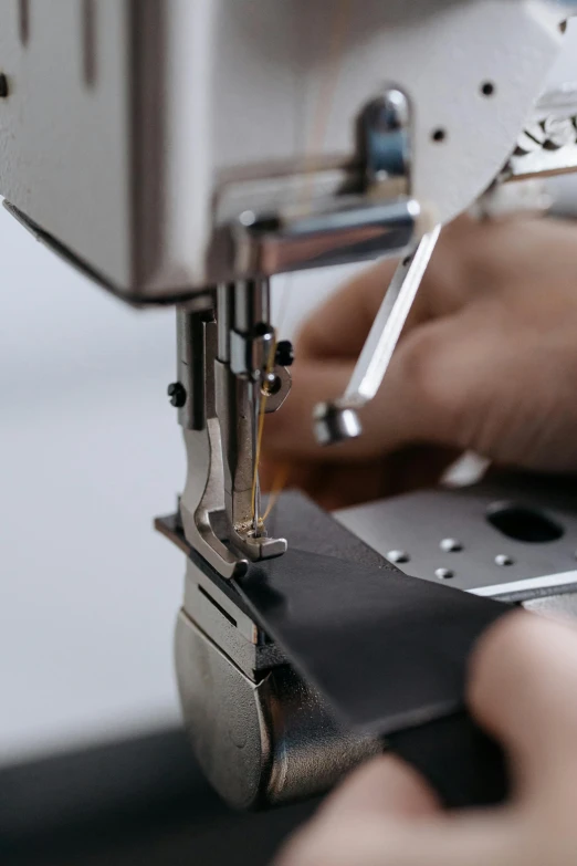 a close up of a person using a sewing machine, cloth and metal, curated collections, brown, digital image