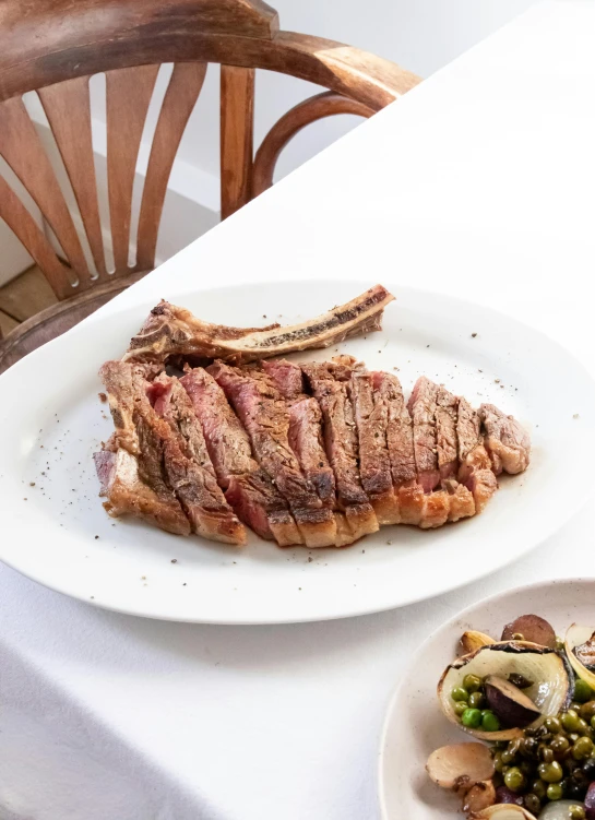 a white table topped with plates of food, rib cage exposed, thick bow, 3/4 side view, manhattan