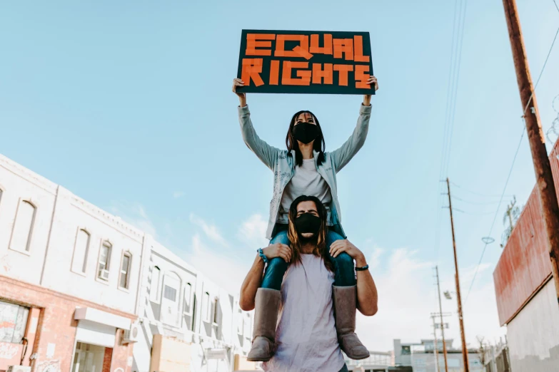 a man riding on the back of a woman holding a sign, trending on pexels, feminist art, full leight, a person standing in front of a, ethics, chromatic