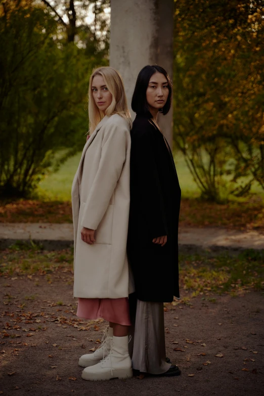 two women standing next to each other in a park, by Anna Boch, minimalism, wearing a long coat, russian and japanese mix, promotional image, [ cinematic