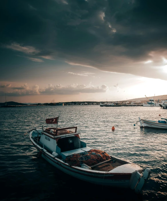a couple of boats sitting on top of a body of water, by Sebastian Spreng, pexels contest winner, greek, dramatic afternoon lighting, low quality photo, fishing