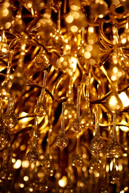 a bunch of wine glasses hanging from a chandelier, inspired by Bruce Munro, baroque, gold dappled light, gold waterfalls, a close-up, golden sacred tree