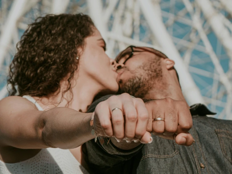 a man and woman kissing in front of a ferris wheel, pexels contest winner, white bandages on fists, background image, close up portrait photo, diverse