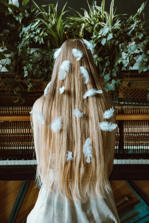 a woman with long blonde hair sitting in front of a piano, inspired by Elsa Bleda, trending on pexels, made of feathers, hair made of trees, back of the hair, 2010s