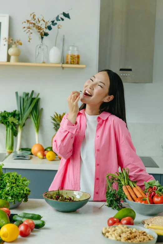 a woman standing in front of a counter full of food, pexels contest winner, happening, earing a shirt laughing, pokimane, veggies, wearing a pink hoodie