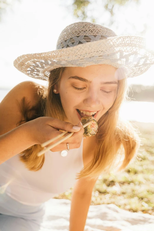 a woman eating a piece of food with chopsticks, unsplash, renaissance, having fun in the sun, portrait of annasophia robb, flower child, on beach