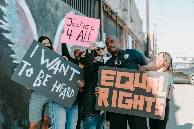 a group of people holding signs in front of a building, by Julia Pishtar, trending on pexels, black arts movement, gay rights, background image, justice, 3 4 5 3 1