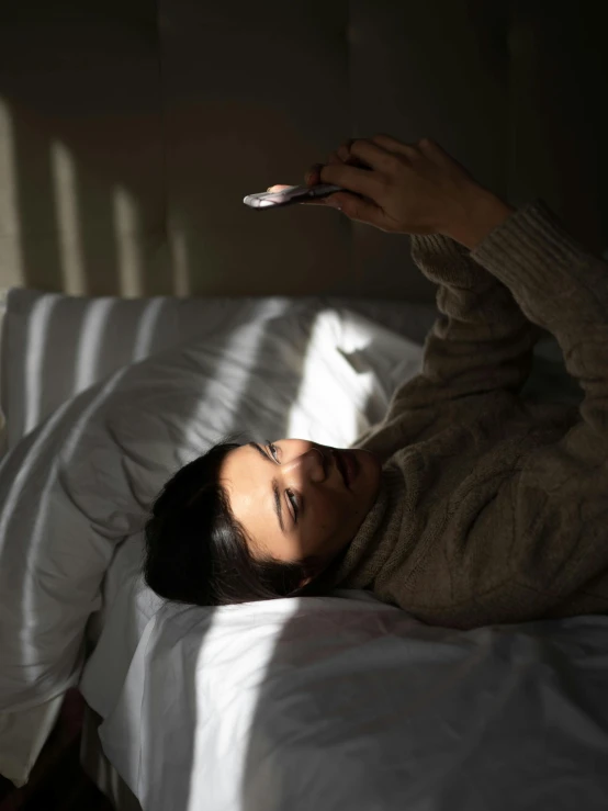 a woman laying in bed reading a book, a polaroid photo, trending on pexels, happening, female image in shadow, cell phone photo, asian woman, reflecting light