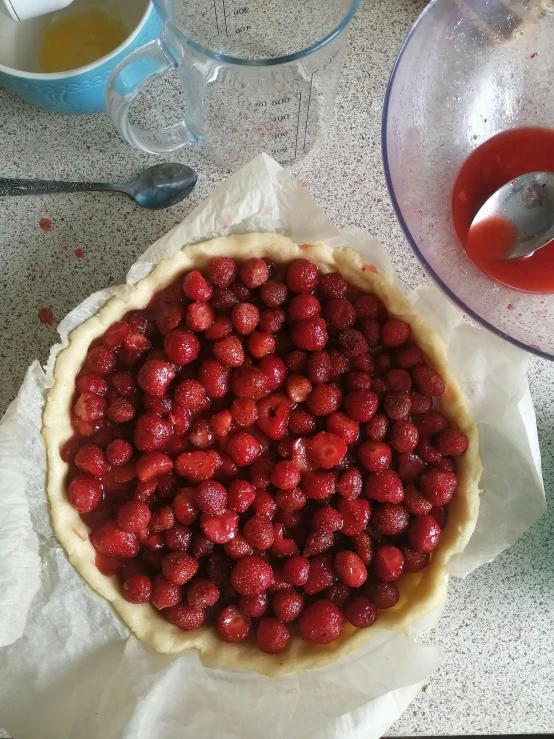 a pie sitting on top of a table next to a bowl of strawberries, red hoods, work in progress, low quality photo, image