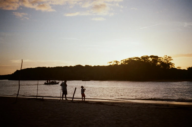 a group of people standing on top of a sandy beach, during a sunset, shot on hasselblad, families playing, fishing