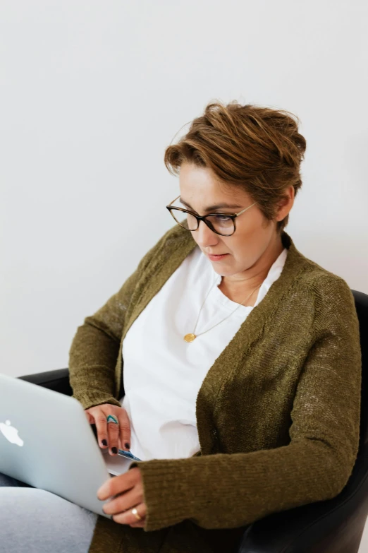 a woman sitting in a chair using a laptop, trending on pexels, renaissance, wearing reading glasses, professional profile picture, middle - age, androgynous person