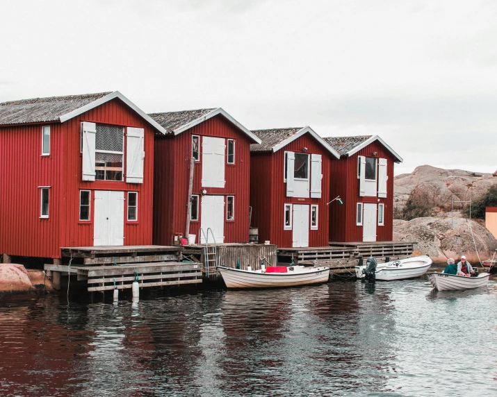 a row of red houses next to a body of water, by Jesper Knudsen, family friendly, shipyard, cabin, brown