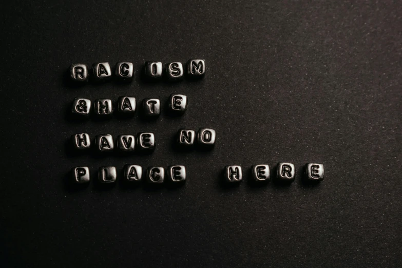 a bunch of metal letters sitting on top of a black surface, by Arabella Rankin, trending on pexels, hatred, man is with black skin, i'm here, dices