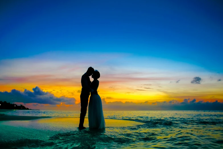 a bride and groom kissing on the beach at sunset, pexels contest winner, avatar image, blue and yellow color theme, on the ocean water, thumbnail