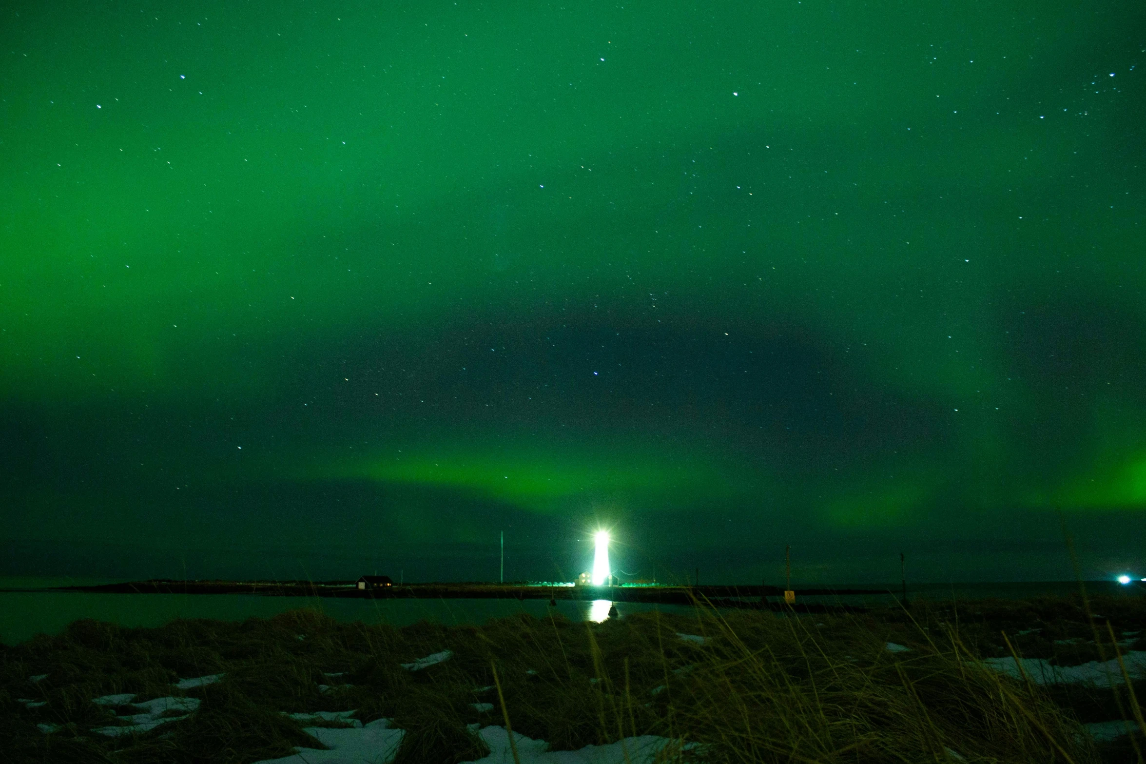 a light house sitting on top of a snow covered field, by Terese Nielsen, pexels contest winner, hurufiyya, green lights, green lightning, from the distance, ultrawide lens”