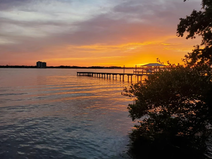 the sun is setting over a body of water, by Carey Morris, pexels contest winner, near a jetty, listing image, sunsetting color, vista view