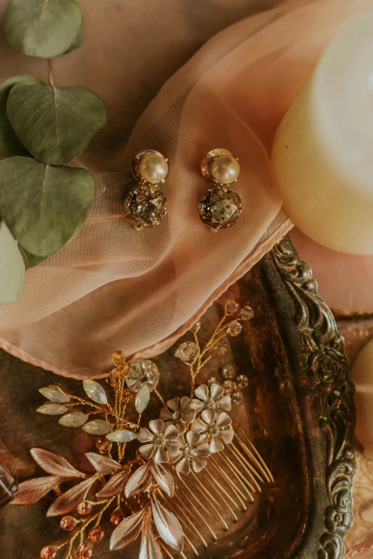 a hair comb sitting on top of a table next to a candle, inspired by Floris van Dyck, baroque, earrings, soft sepia tones, floral bling, detail shot