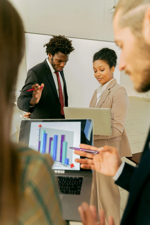 a group of people standing around a laptop