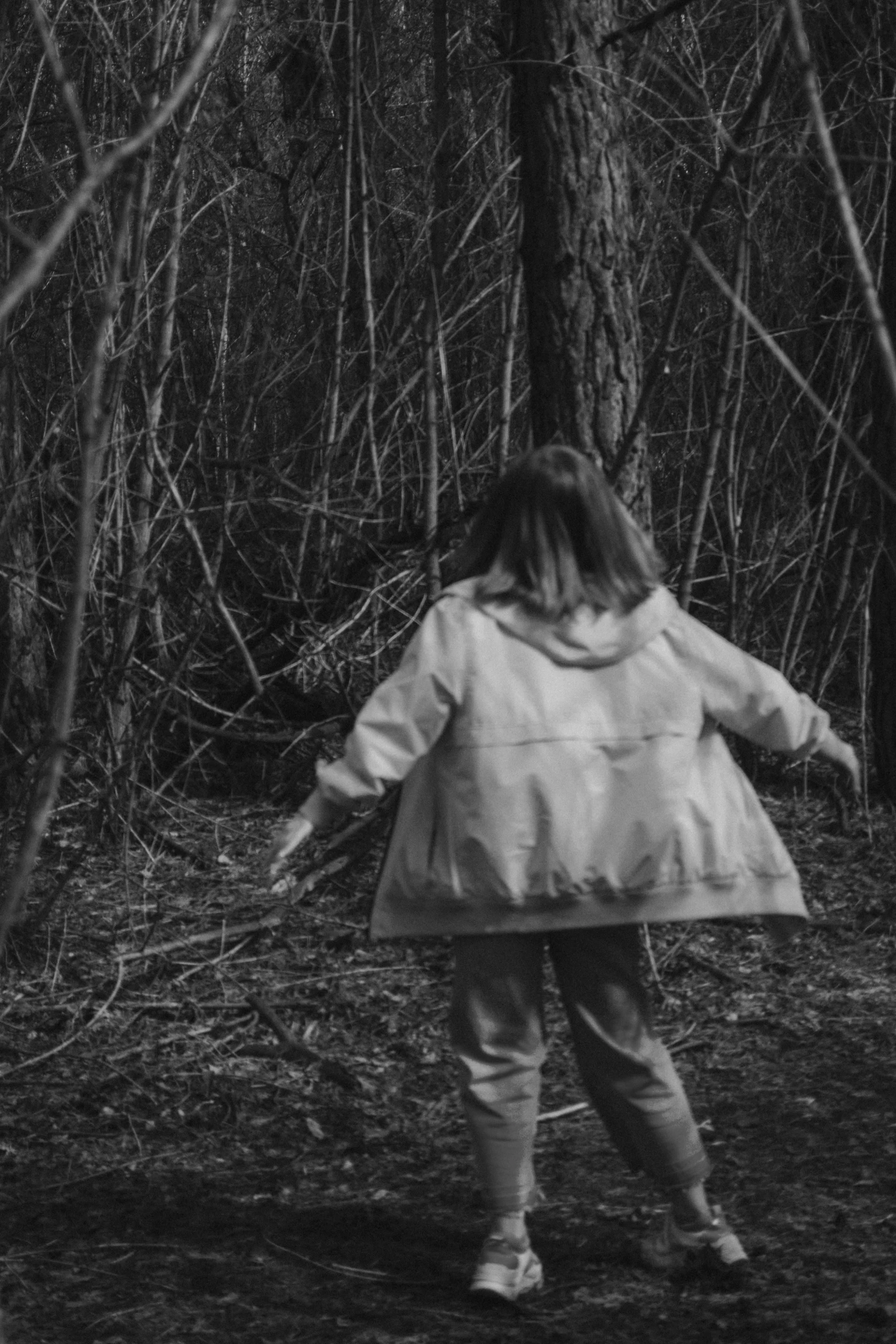 a black and white photo of a person walking in the woods, inspired by Kati Horna, unsplash, conceptual art, creepy child, vhs footage still, action shot girl in parka, pulling the move'the banshee '