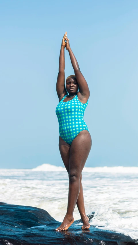 a woman standing on top of a surfboard in the ocean, blue checkerboard dress, dark skinned, plus-sized, fullbodysuit