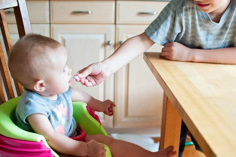 a woman feeding a baby in a high chair, pexels contest winner, kid named finger, on kitchen table, caring fatherly wide forehead, thumbnail