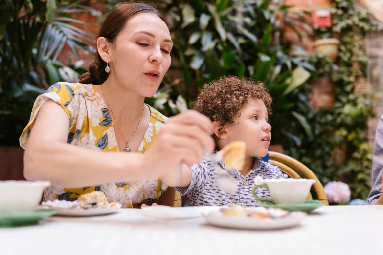 a woman sitting at a table with two children, by Nicolette Macnamara, pexels, eating cheese, emma bridgewater and paperchase, manuka, fine dining