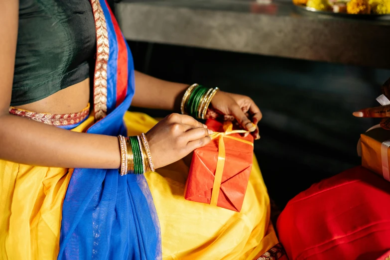 a close up of a person holding a gift, pexels contest winner, hurufiyya, dressed in a sari, primary colours, vriska serket, thumbnail