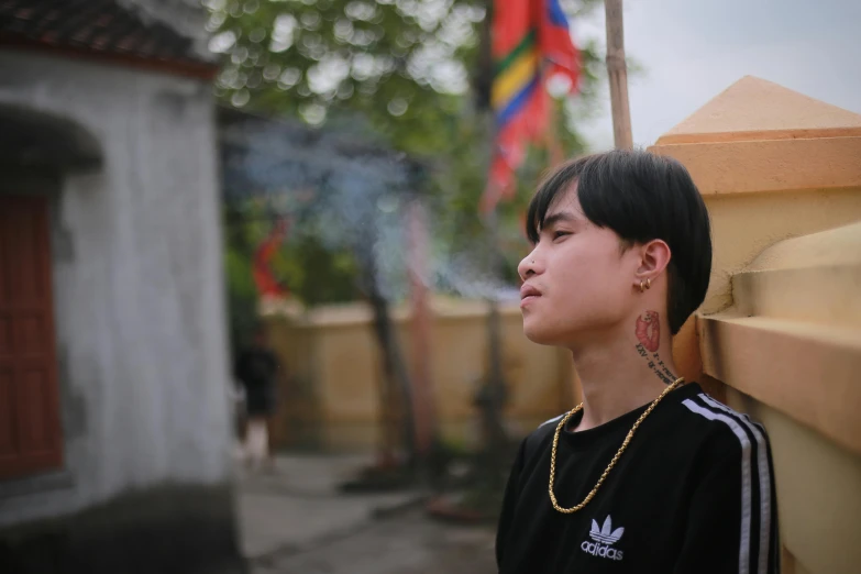 a young man standing in front of a building, inspired by Gang Hui-an, pexels contest winner, realism, vietnamese temple scene, queer woman, profile image, thoughtful )