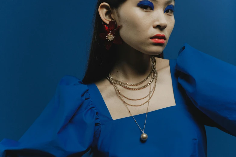 a woman with long hair wearing a blue dress, inspired by Elsa Bleda, trending on pexels, rococo, wearing several pendants, korean women's fashion model, gold and red, wearing pearl earrings