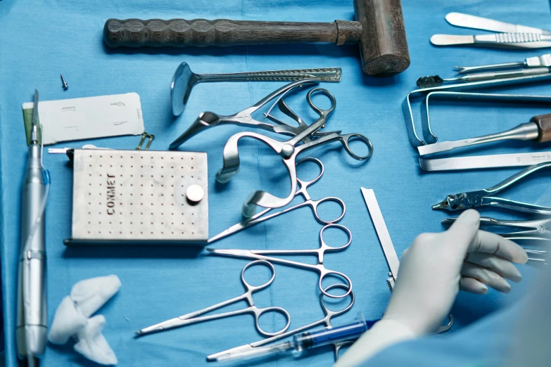 a bunch of tools sitting on top of a blue table, hurufiyya, surgery theatre, profile image, compassionate, miscellaneous objects