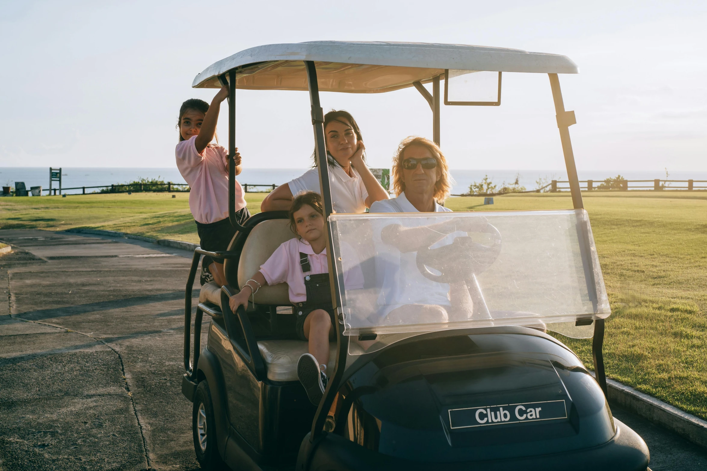 a group of people riding in a golf cart, olivia de bernardinis, little kid, colour corrected, clubs