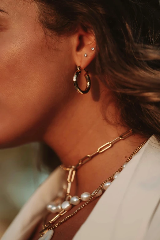 a close up of a woman wearing a necklace and earrings, by Julia Pishtar, gold hoop earings, pearls and chains, mix of styles, different angles