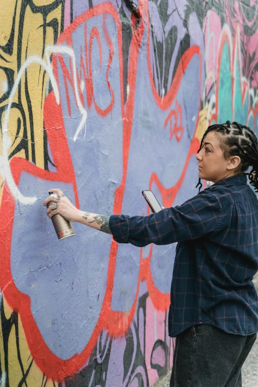 a woman spray painting graffiti on a wall, lgbtq, 2019 trending photo, rapper, small in size