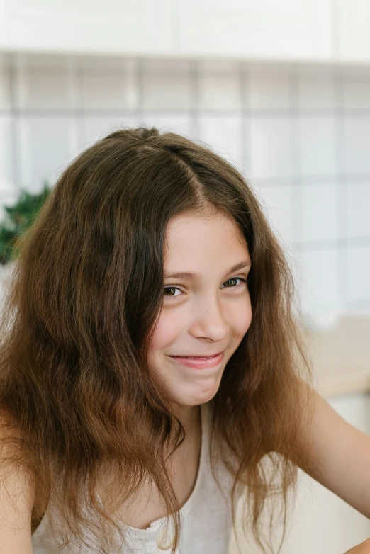 a woman sitting at a table with a plate of food, brown fluffy hair, greta thunberg smiling, low quality photo, solid background