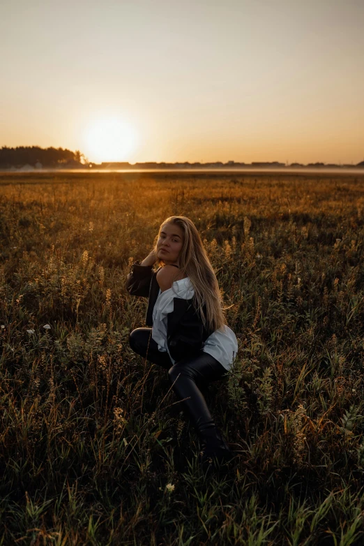 a woman sitting in a field at sunset, unsplash contest winner, casual pose, dasha taran, low quality photo, fall season