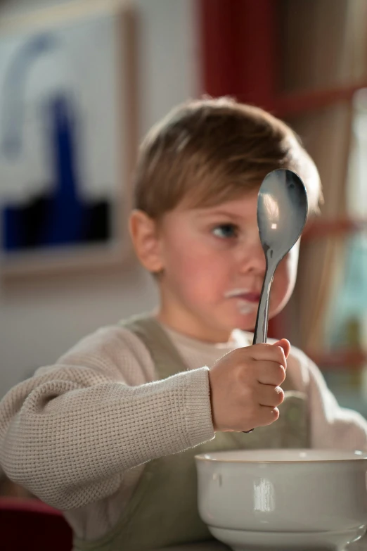 a little boy sitting at a table with a spoon and bowl, inspired by Albert Anker, instagram, made of brushed steel, award - winning, mirrored, grey