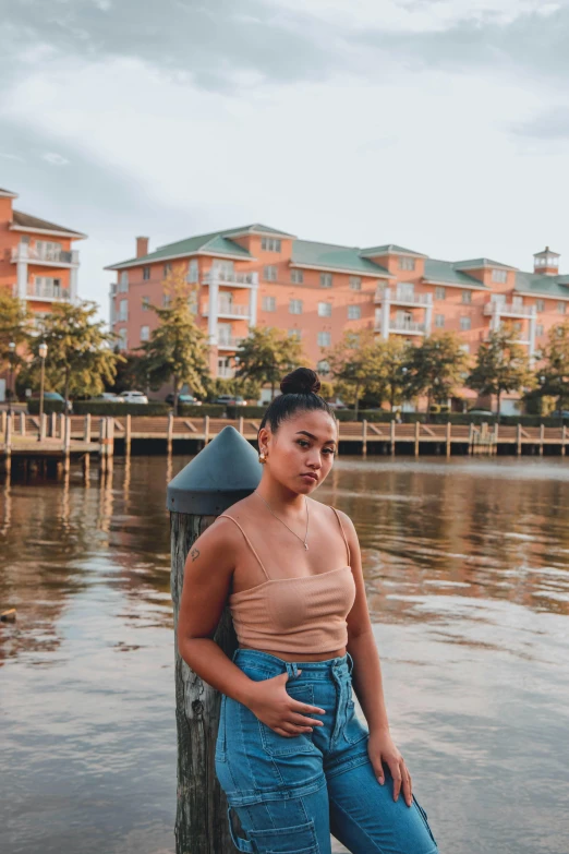 a woman standing on a dock next to a body of water, in savannah, mixed race woman, profile image, thicc