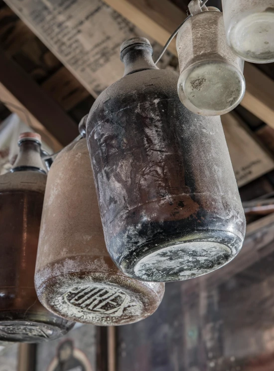 a number of jars hanging from a ceiling, a portrait, unsplash, jacob riis, closeup photograph, weathered, beer