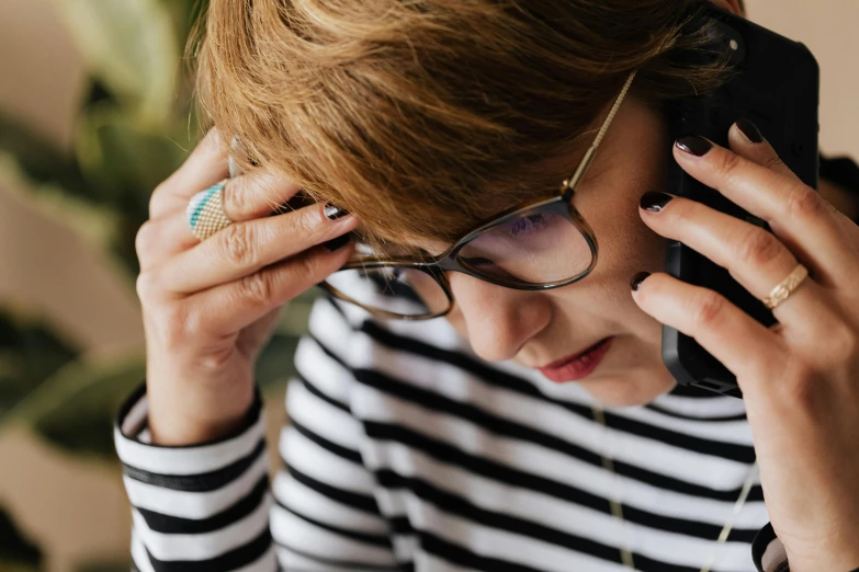 a woman with glasses talking on a cell phone, by Julia Pishtar, trending on pexels, devastated, square rimmed glasses, working in a call center, sorrow intense likely