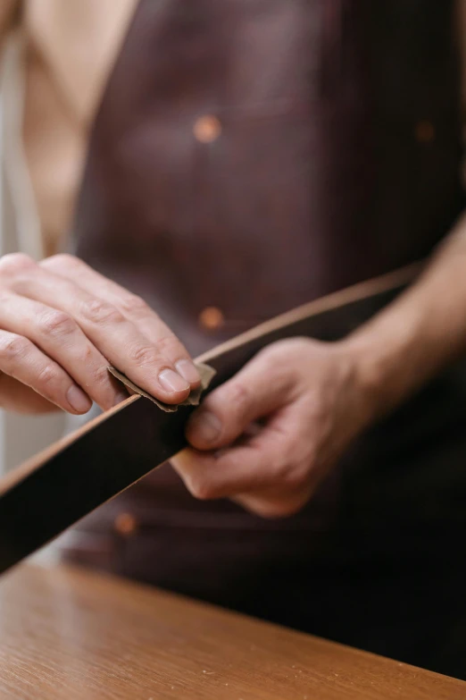 a person cutting a piece of leather with a knife, a portrait, by David Simpson, trending on pexels, many belts, bending down slightly, thumbnail, ribbon