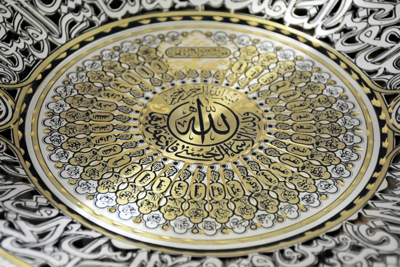 a silver and gold plate with arabic writing on it, a detailed painting, trending on pixabay, hurufiyya, made out of shiny white metal, gold and black color scheme, sun light, highly detailed carvings