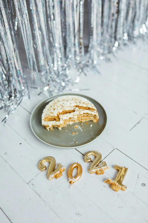 a plate that has a piece of cake on it, trending on pexels, happening, new years eve, white metallic, photo of the year 2 0 2 2, goldilocks