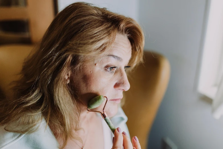 a woman sitting in a chair with a flower in her mouth, by Emma Andijewska, trending on pexels, holding a wooden staff, pronounced facial contouring, middle - age, blurred