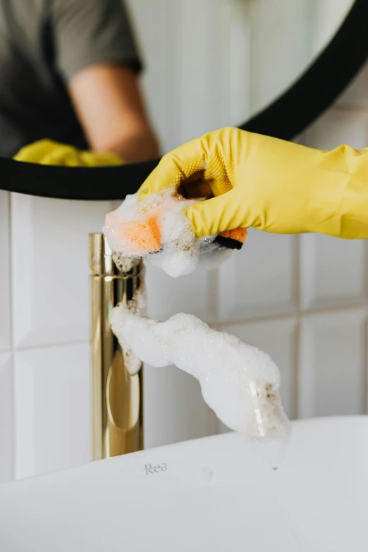a person in yellow gloves cleaning a bathroom sink, a portrait, pexels, iridescent soapy bubbles, gold, detailed product image, tall